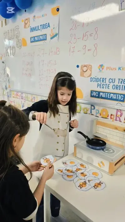 Două fete la un joc de matematică în sala PlusKids, în fața tablei cu exerciții de scădere